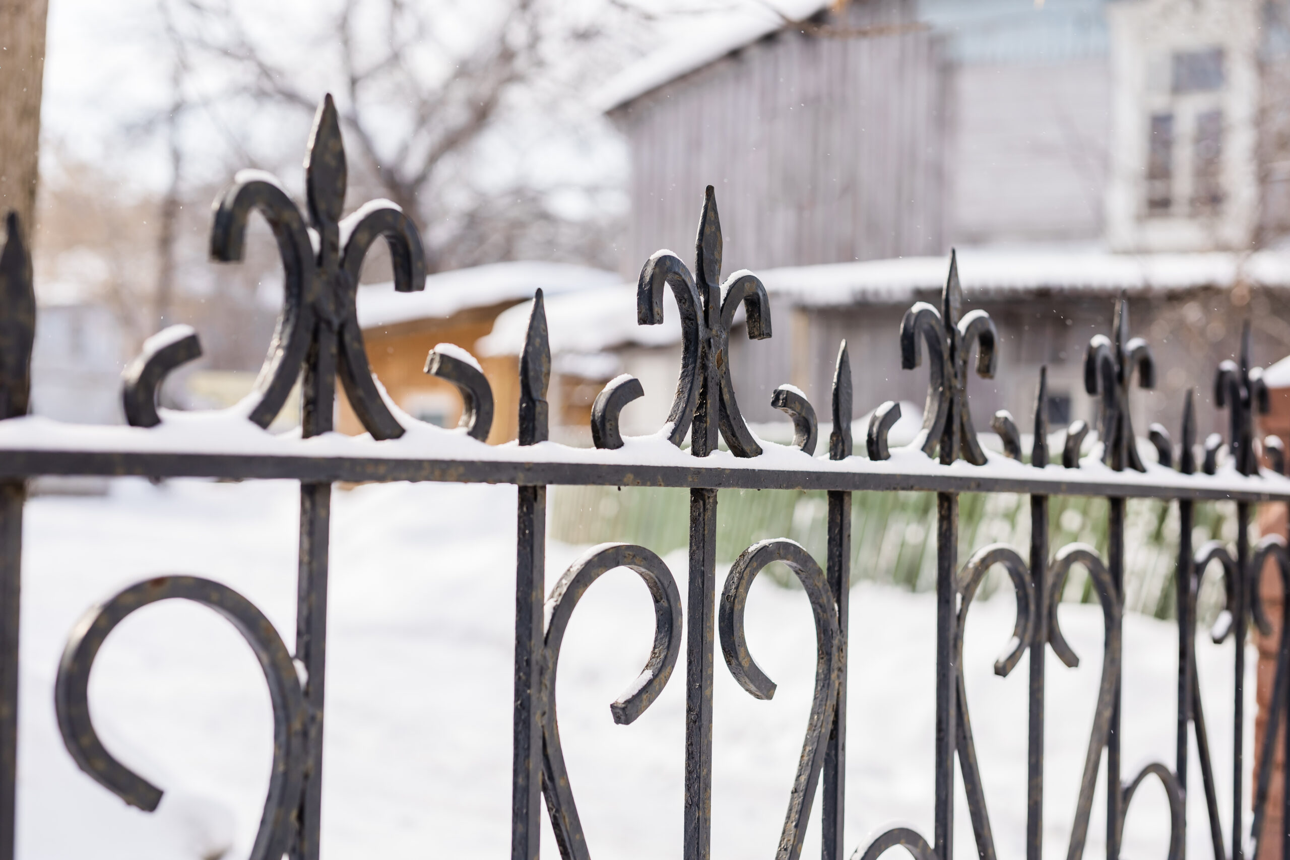 Elements of ornamental ornament in a metal forged fence are covered with snow in winter season.