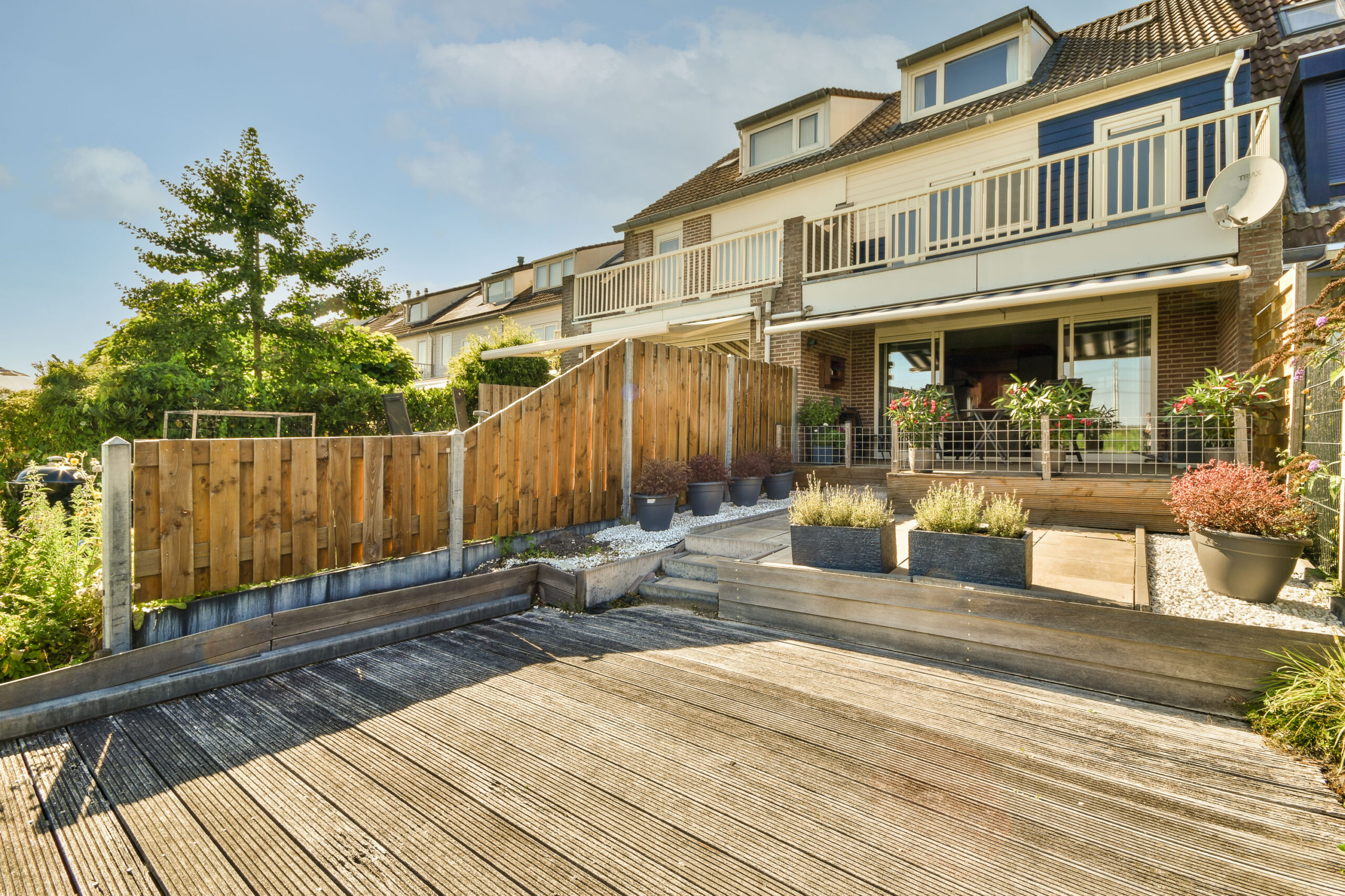 Neat paved patio with sitting area and small garden near wooden fence
